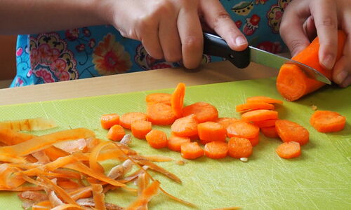 Kinder schälen und schneiden die Karotten