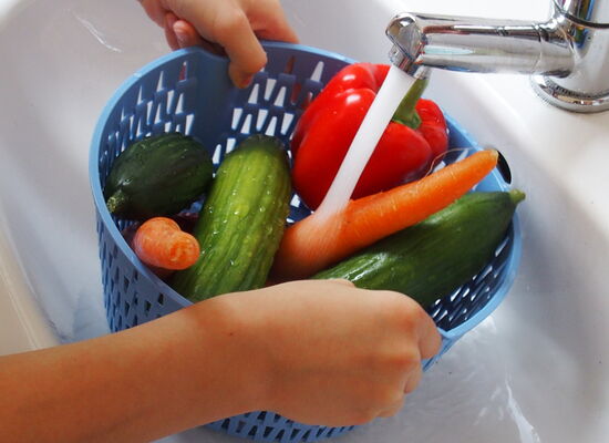 Ein Korb voller Gemüse wird gewaschen