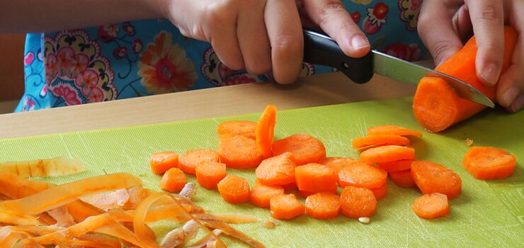 Kinder schälen und schneiden die Karotten